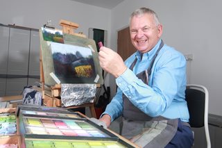 a man smiling and pointing at a box of pizzas