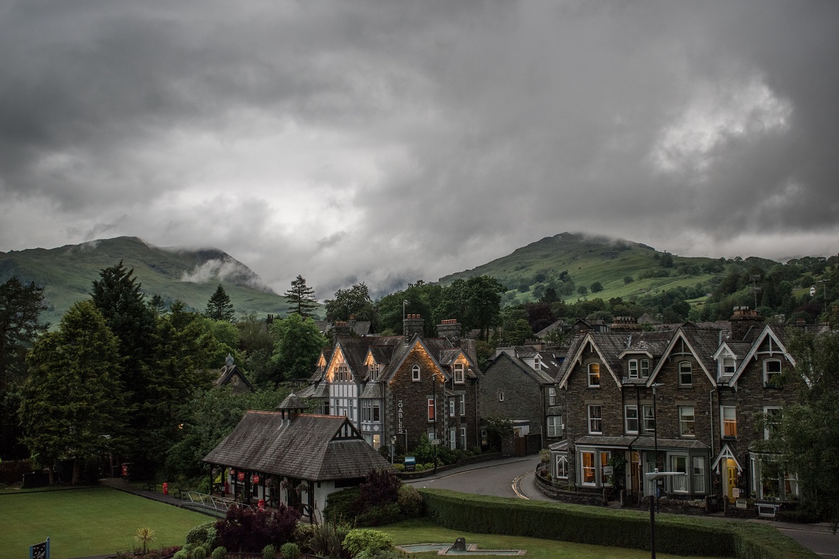 A cosy village on a cloudy day with green hills in the background