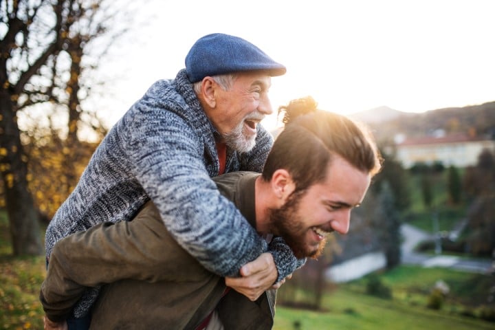 The history of fathers day illustrated by a son giving his older dad a piggy back.