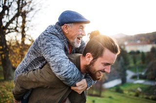 The history of fathers day illustrated by a son giving his older dad a piggy back.