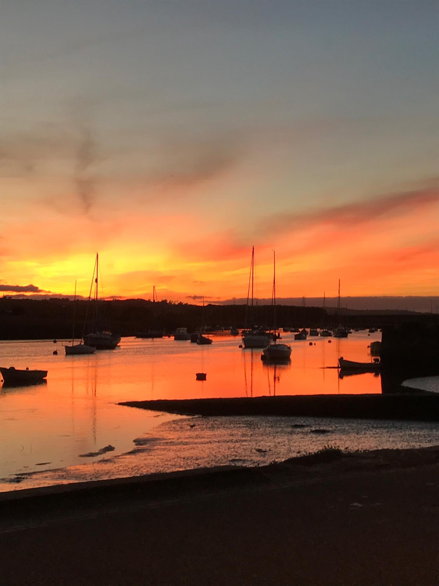a body of water with boats in it and a sunset in the background