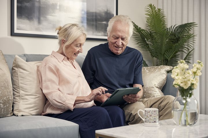 a man and a woman sitting on a couch looking at a book