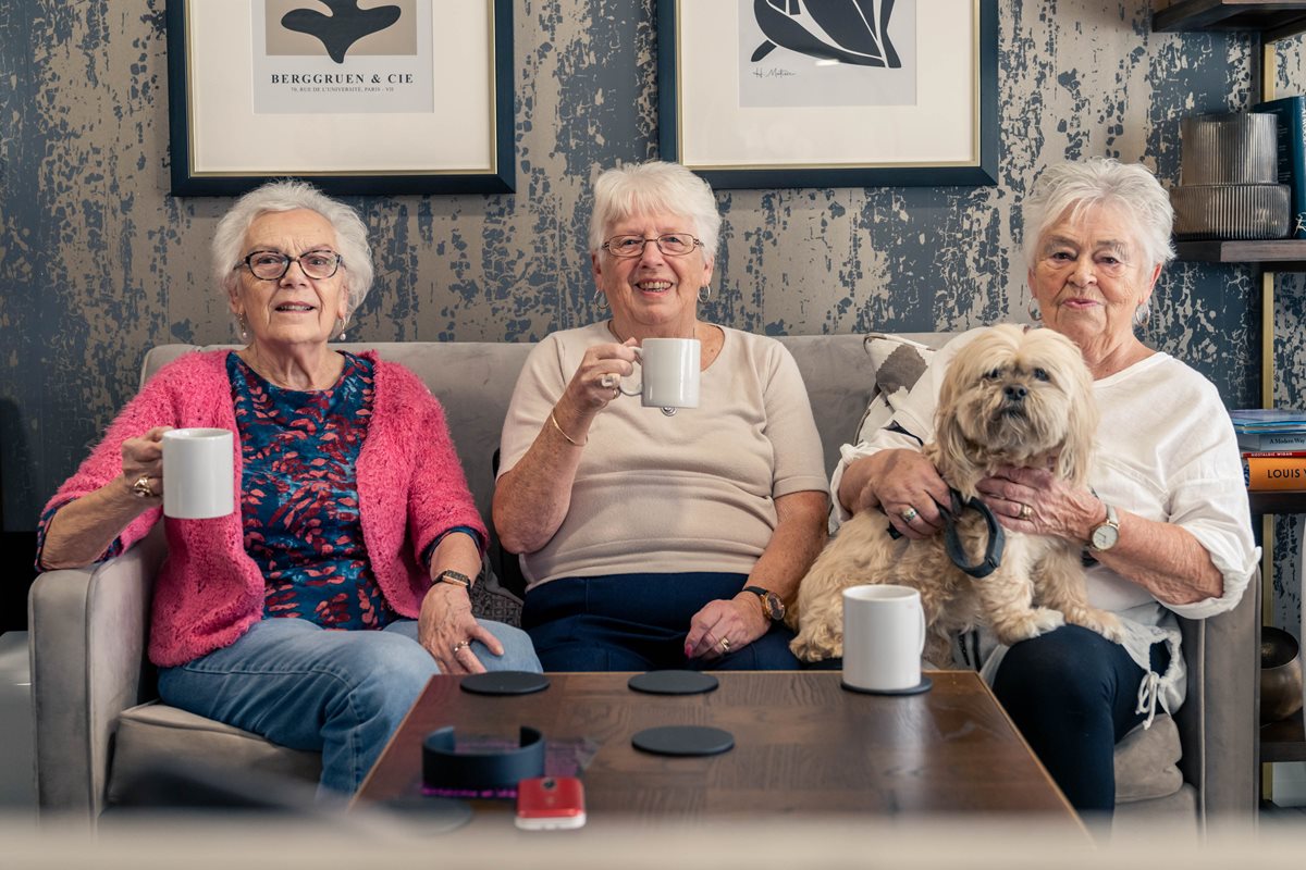 a group of women sitting on a couch with a dog