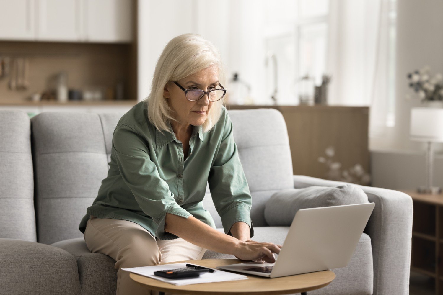 A woman sitting on a couch using a laptop to check entitlements
