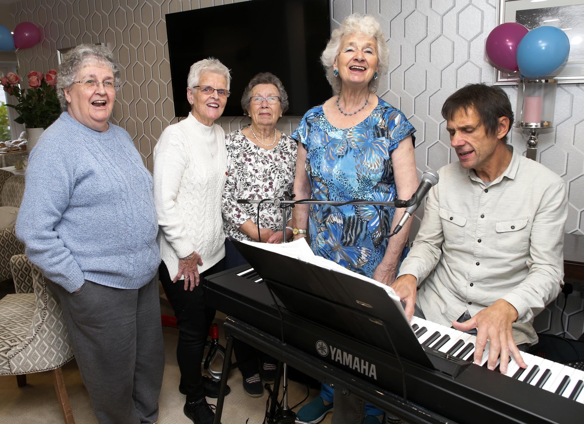 a group of people standing around a piano