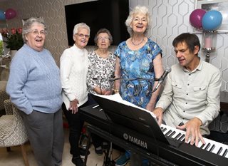 a group of people standing around a piano