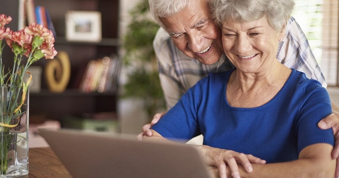 a man and woman smiling at a laptop