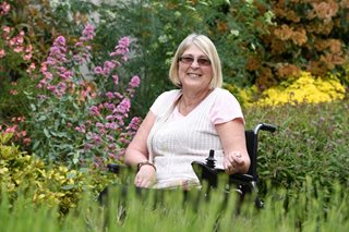 Veronica smiling, whilst sitting in a garden in bloom