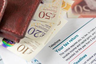 A wallet and British banknotes on top of a tax return letter.