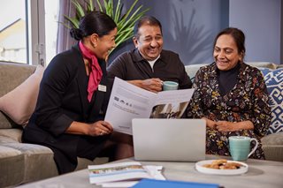 A senior couple looks happy as they discuss the next steps towards their rental retirement property with a McCarthy & Stone professional