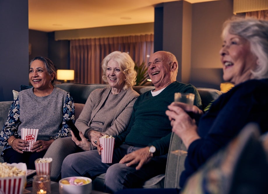 Older people smiling and laughing while watching a film in a beautiful lounge