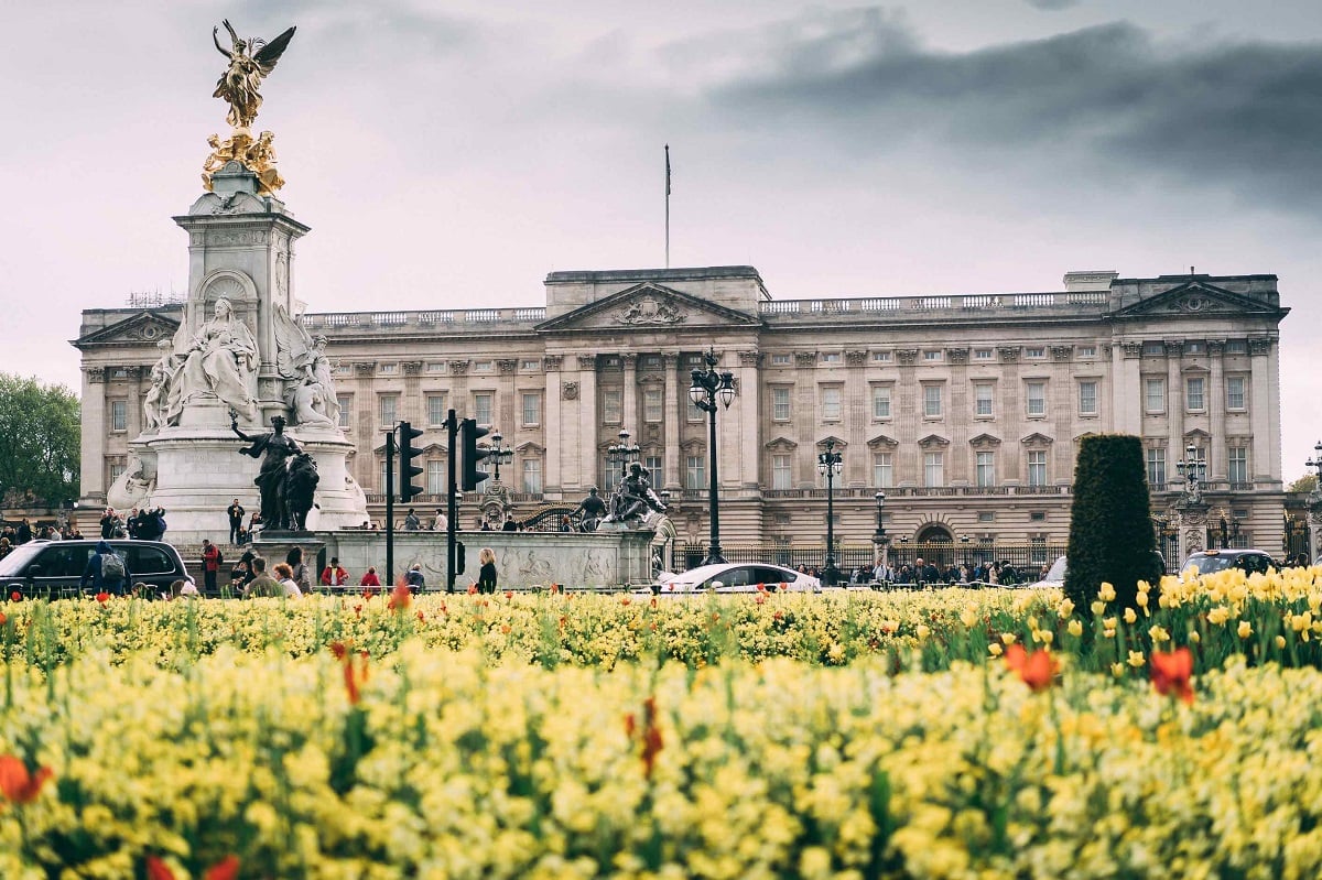 a large building with a statue in front of it with Buckingham Palace in the background