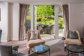 A stylish living room of a McCarthy & Stone property, featuring large doors that open out to a garden patio.
