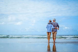 A retired couple walking on the beach.
