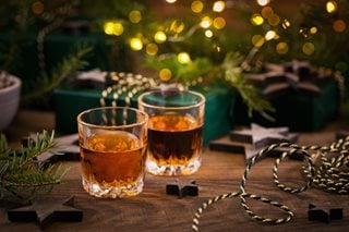 Two shot glasses of 'Christmas pudding vodka' on a festive decorated table.