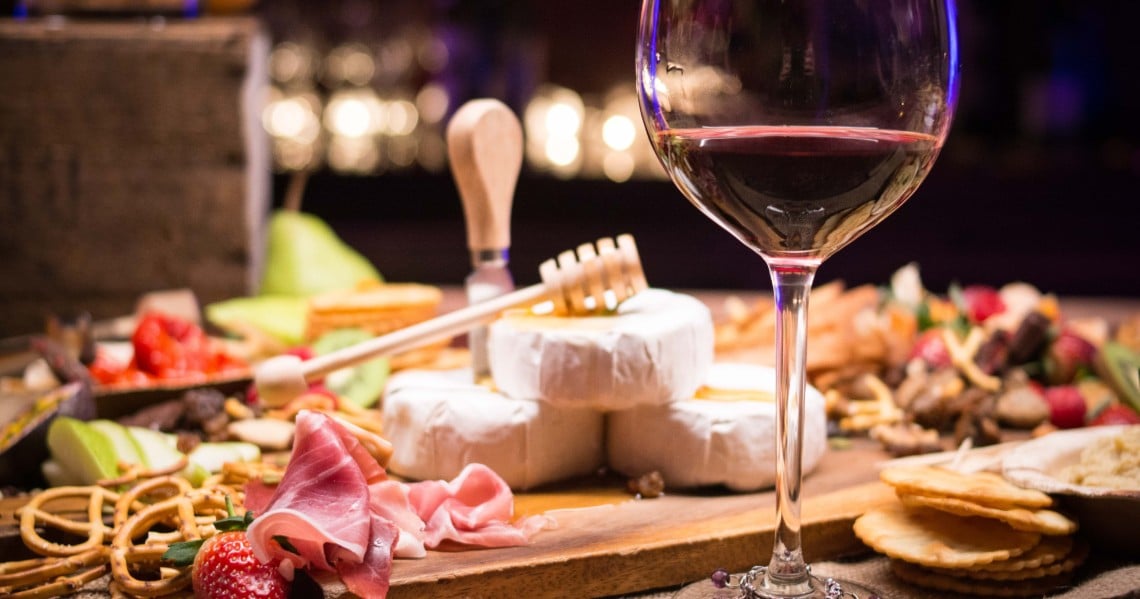 a glass of wine next to a plate of desserts