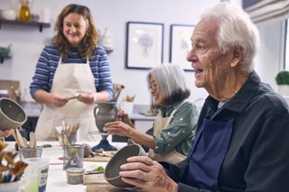 a group of people sitting at a table painting