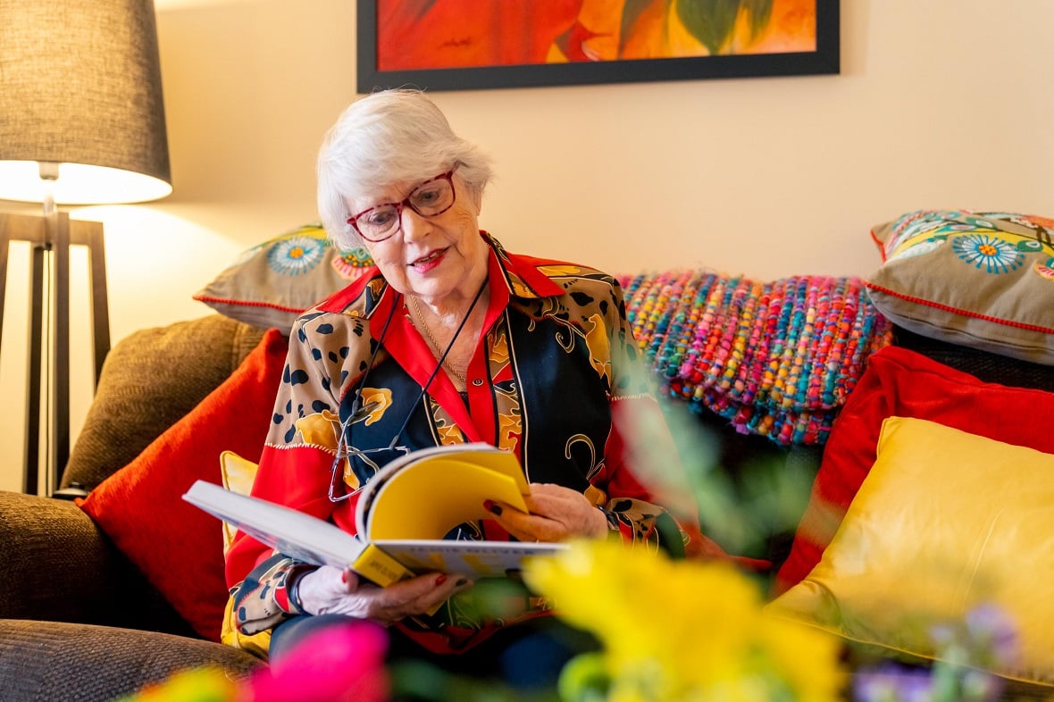 Ann reading a book on her sofa