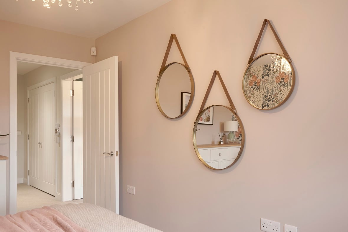 Bright hallway in a retirement apartment, with one wall featuring 3 large teardrop-shaped mirrors.