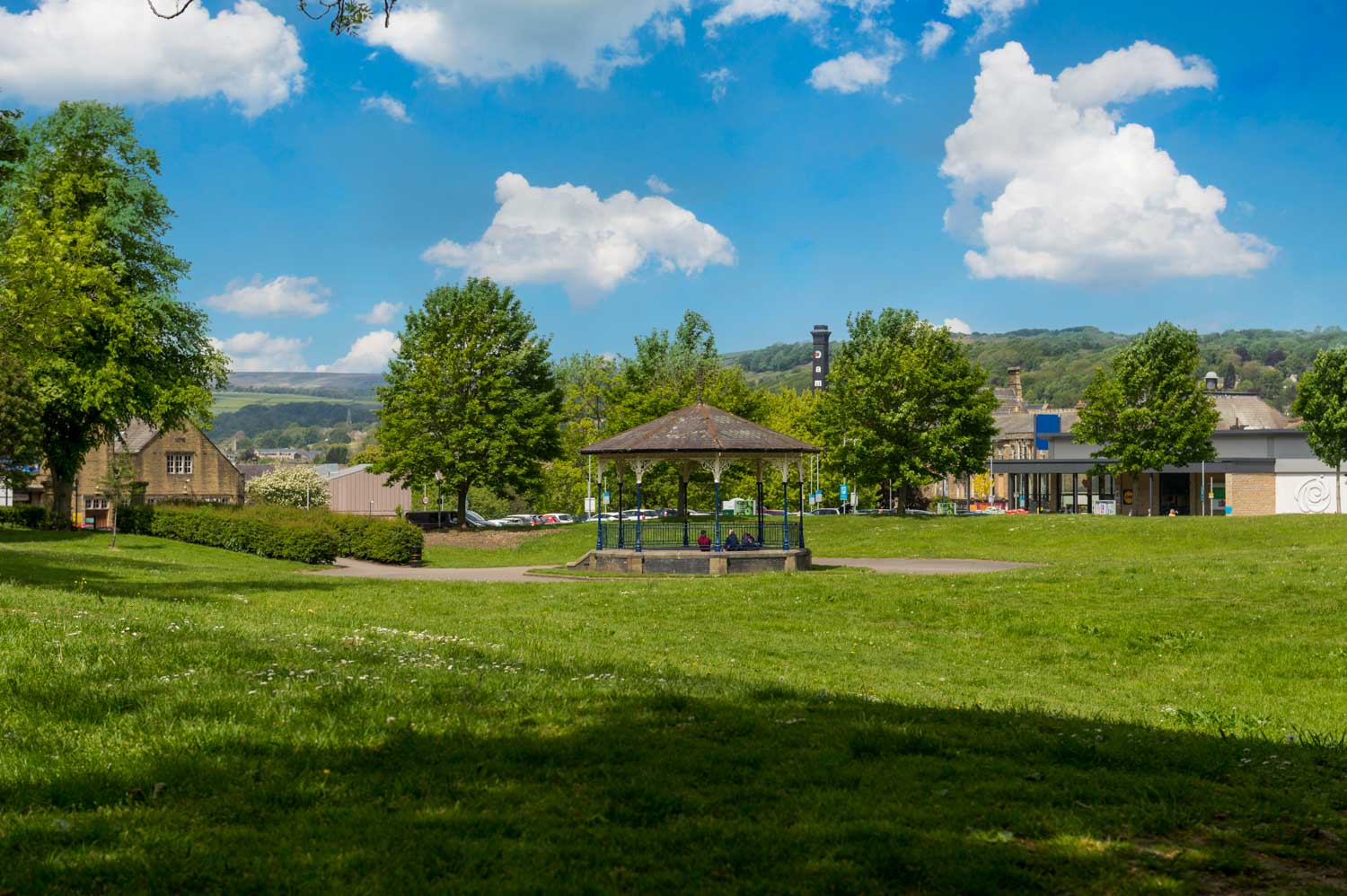 a grassy area with buildings and trees in the background
