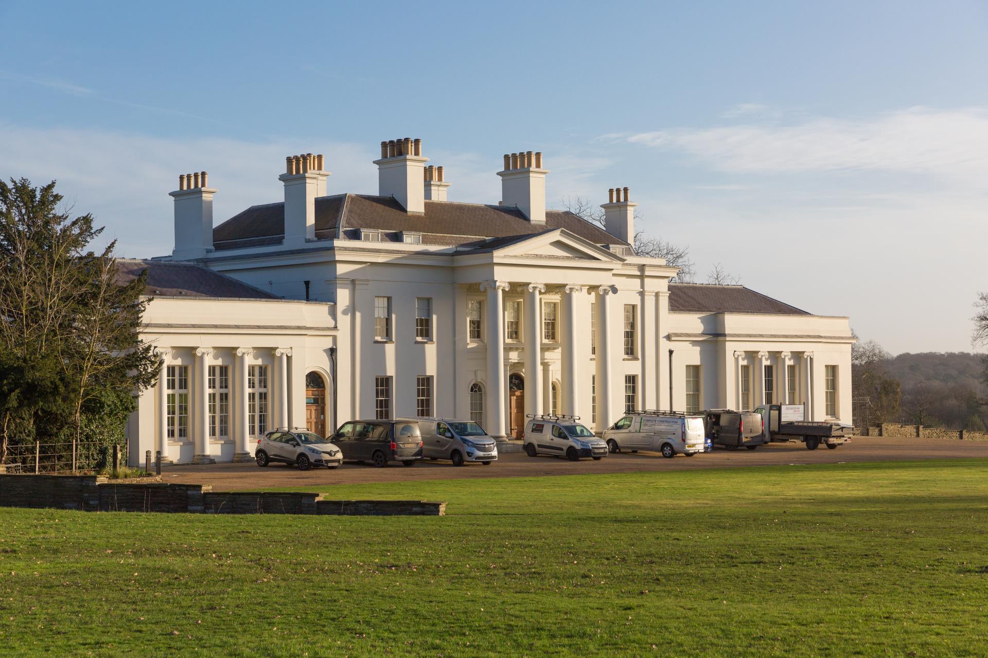 a large white house with cars parked in front of it with Hylands House in the background