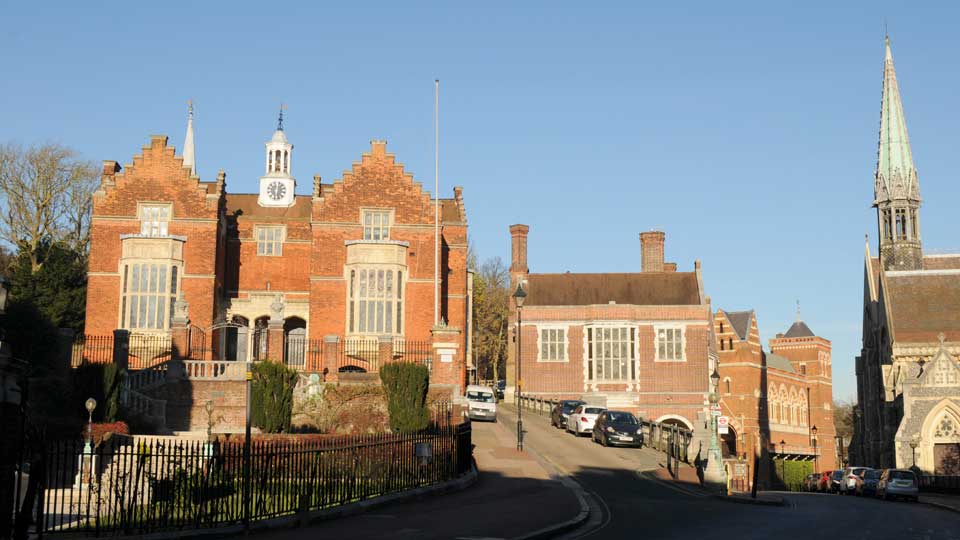 a street with cars parked on the side and a building with a clock tower on the top