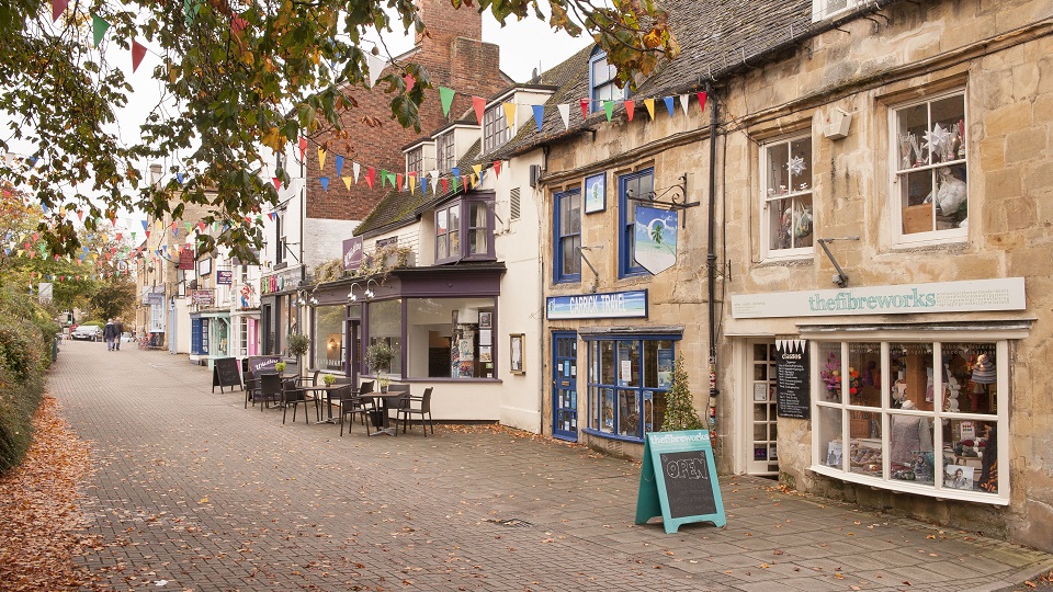 a cobblestone street with tables and chairs and a sign