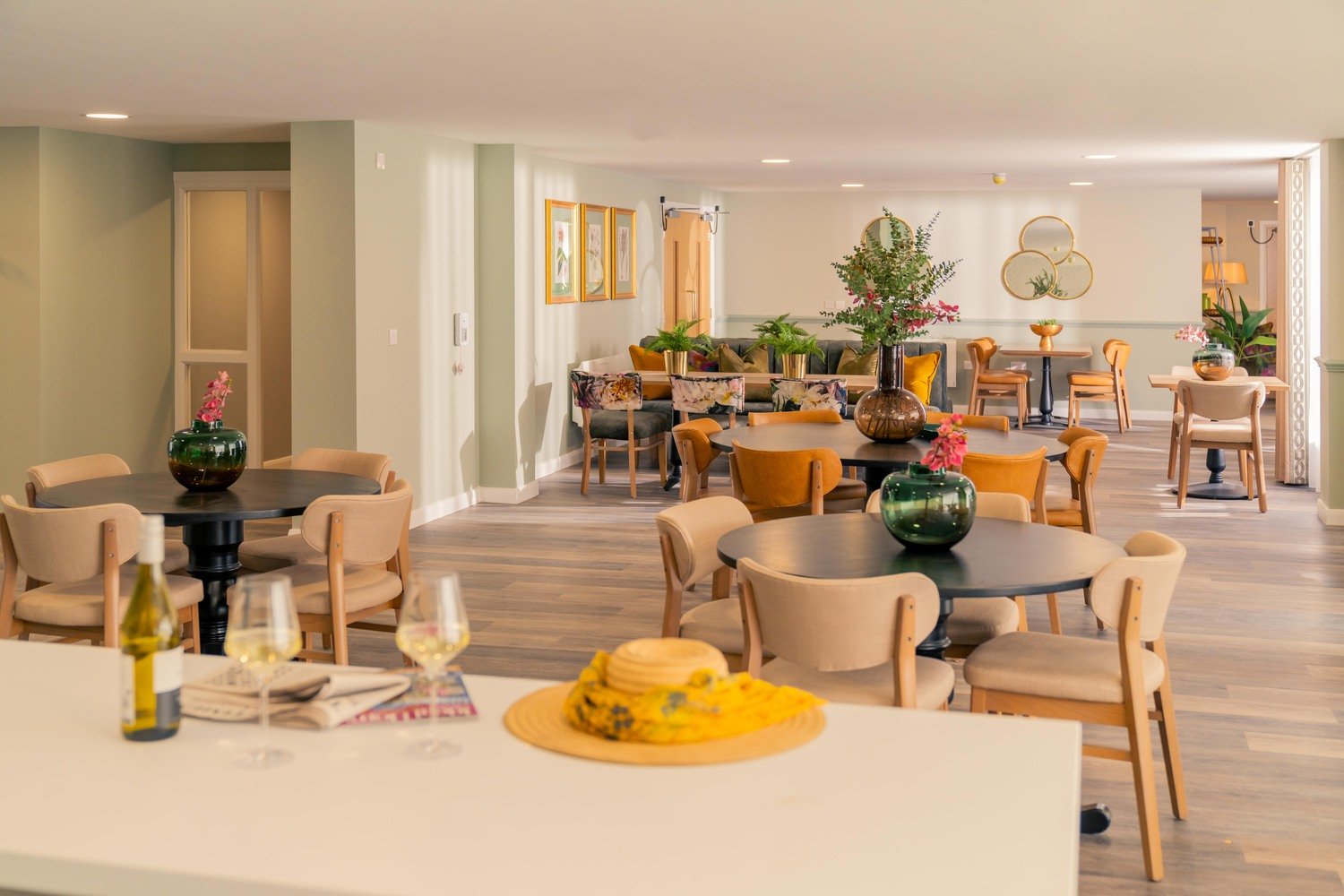 A bottle and two glasses of wine and a newspaper in the kitchen area of a retirement development lounge.