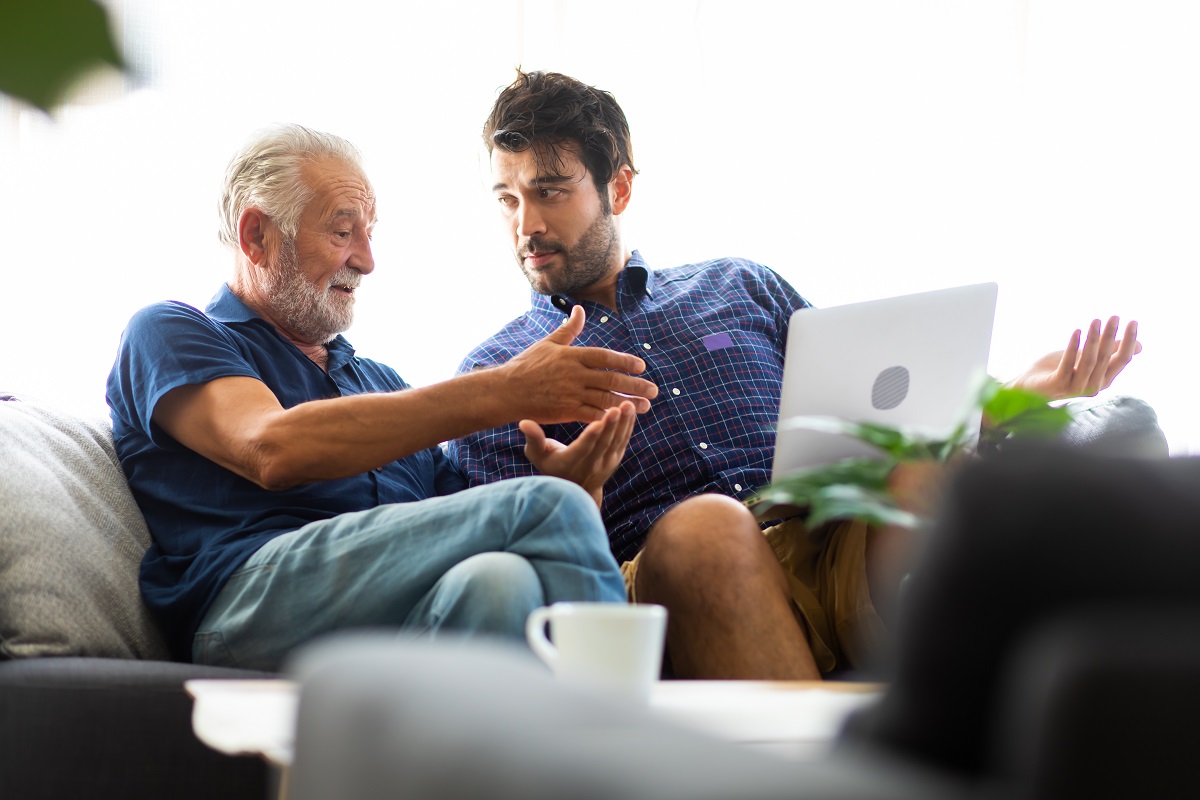 Son and elderly father talking in an animated manner about retirement living