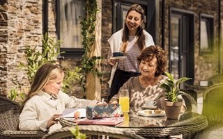 mum, daughter and granddaughter sitting at a table with food and drinks