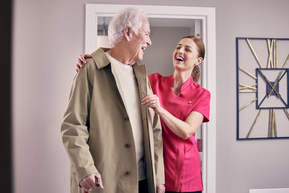 A member of the McCarthy Stone team helping a senior resident, looking at one another while laughing.
