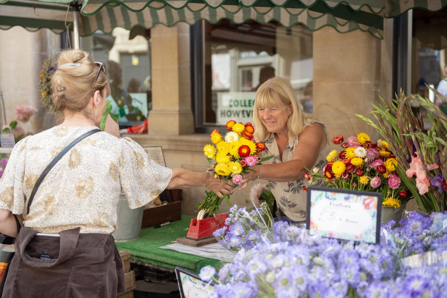 A florist hands a bouquet of flowers to a customer at a market in Stamford, Lincolnshire.