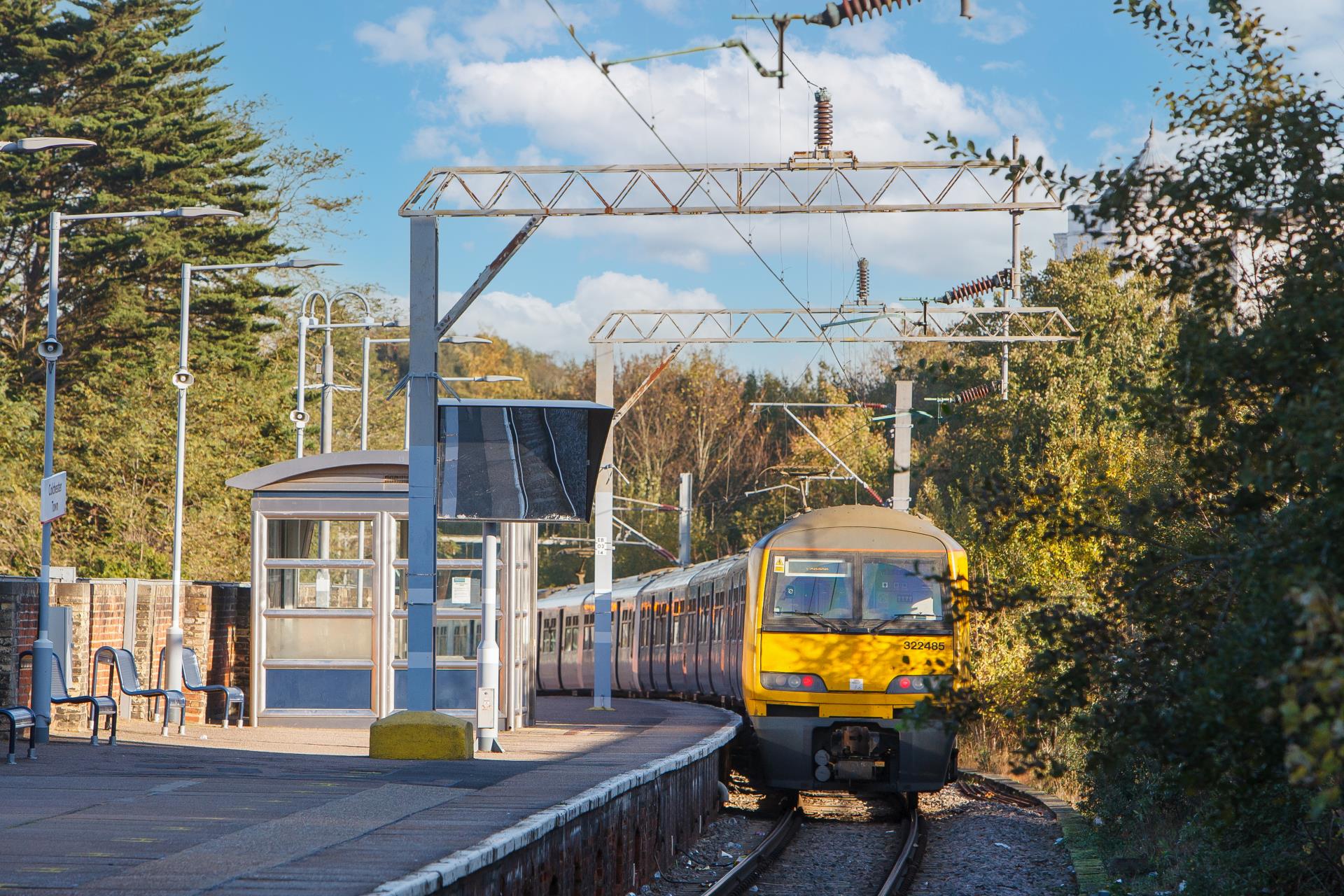 A yellow train on the platform at Colchester train station.