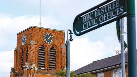 a clock tower behind a street sign
