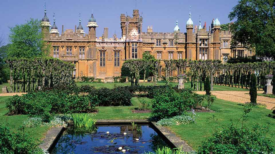 a large building with a fountain in front of it with Knebworth House in the background