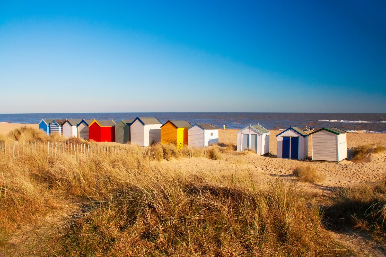 A row of colourful beach huts looking out to see in Southwold, Suffolk.