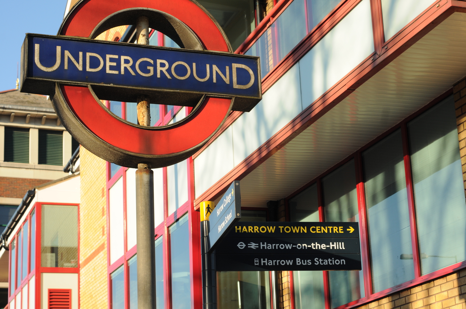 The London Underground sign in Harrow, and a signpost for the bus station and train station.