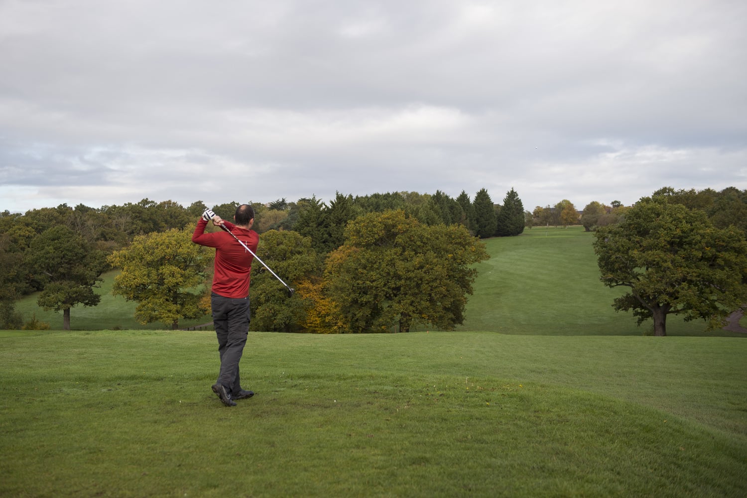 A man swinging a golf club at Trent Park Golf Club.