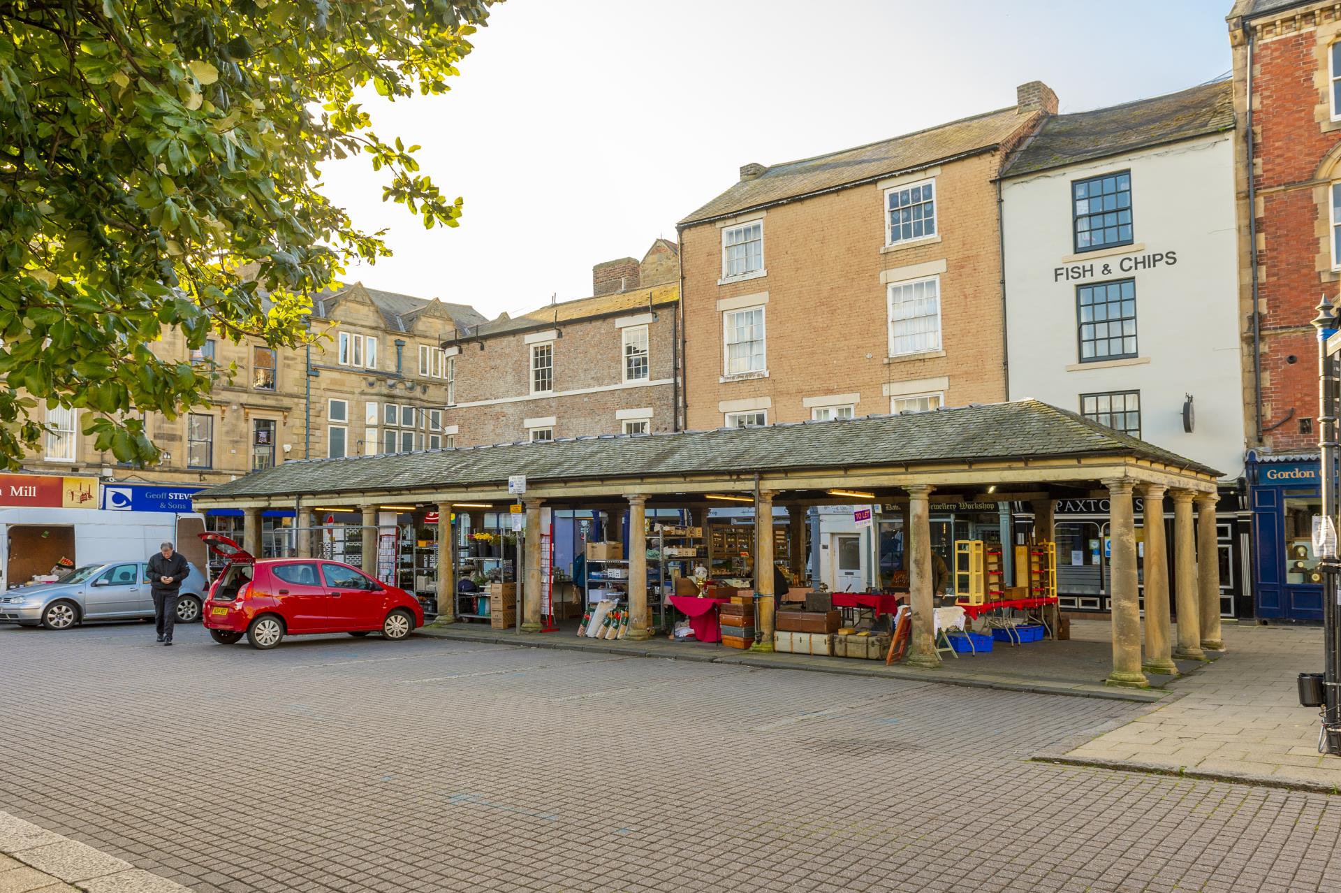 a brick street with a storefront and cars parked on the side