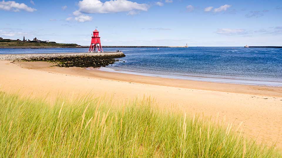 a beach with a red tower and water in the background