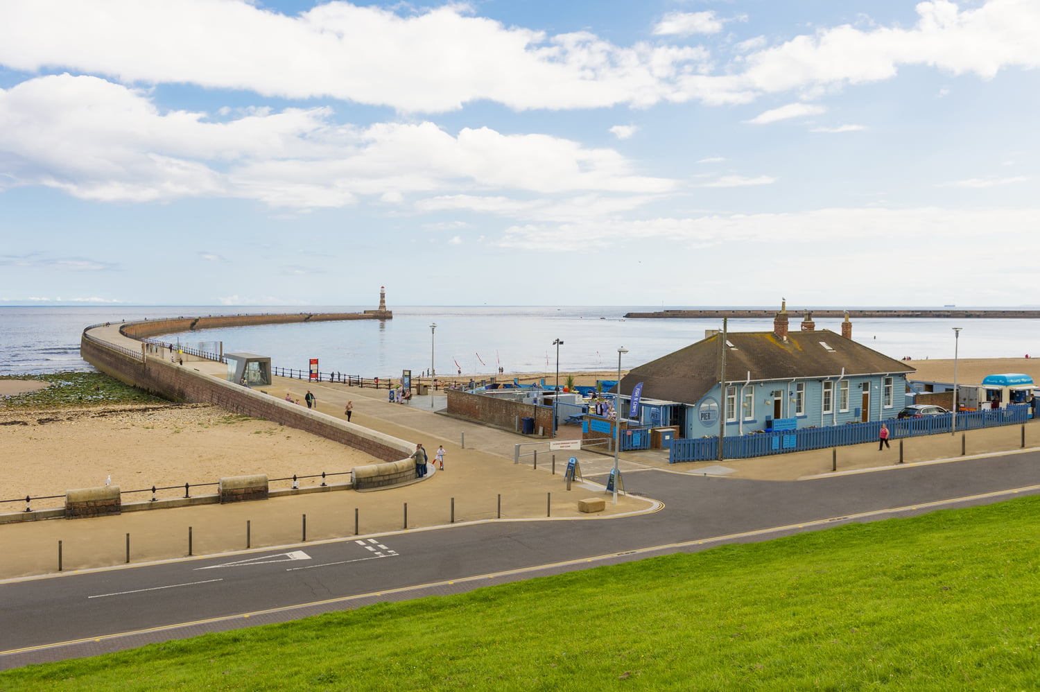 A beachfront and building in front of Roker Pier and Lighthouse.