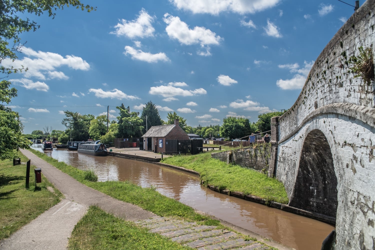 An arched bridge over the Shropshire Union Canal with boats moored at the Nantwich Canal Basin.