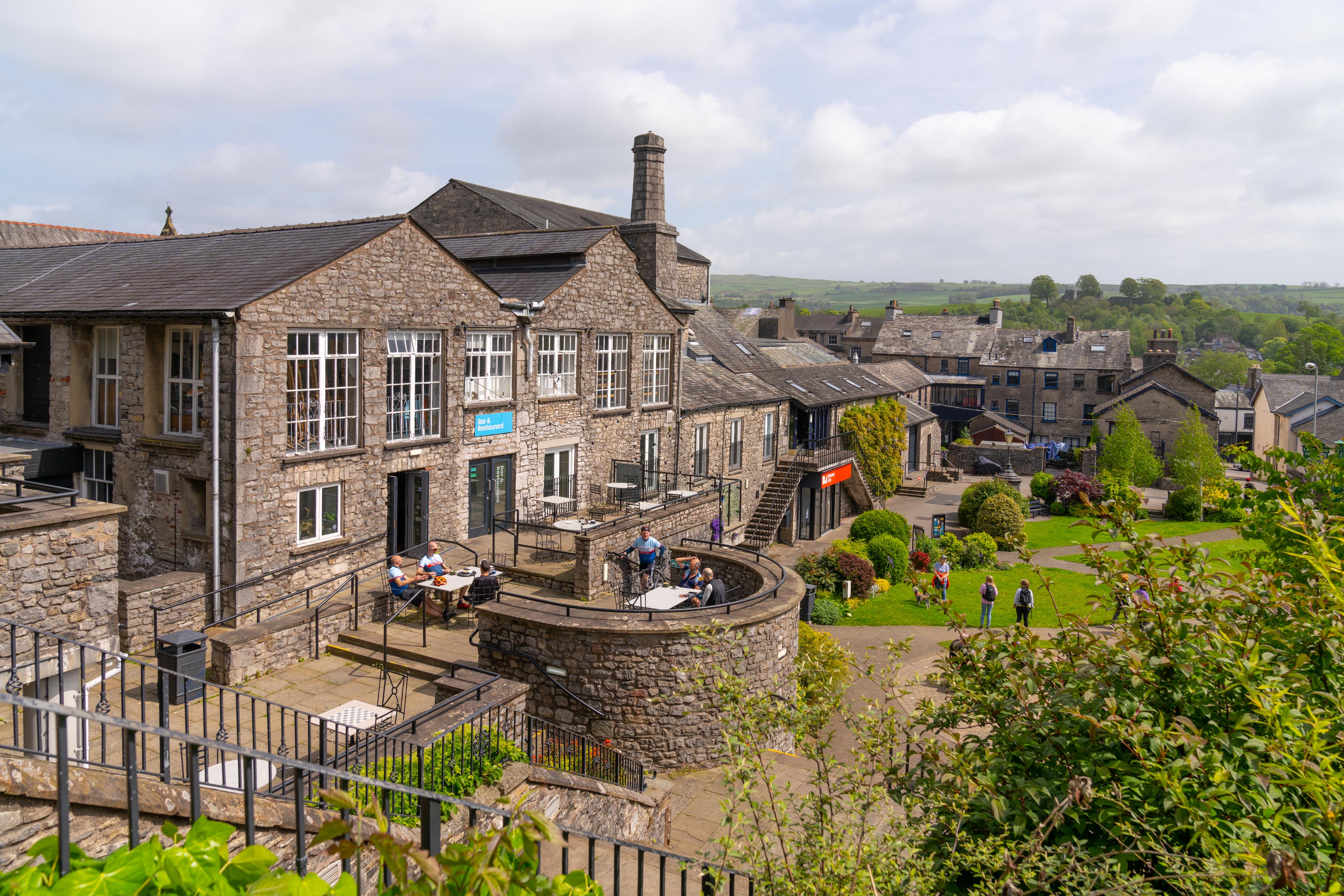 a stone building with a group of people on a bench and a group of people sitting on a