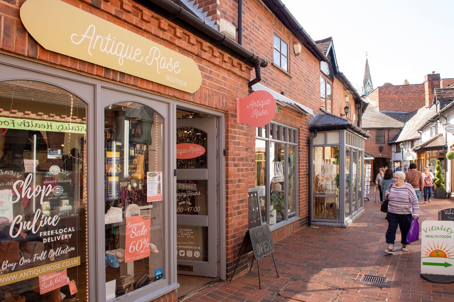 A retired lady walks outside various shops in Wokingham centre.