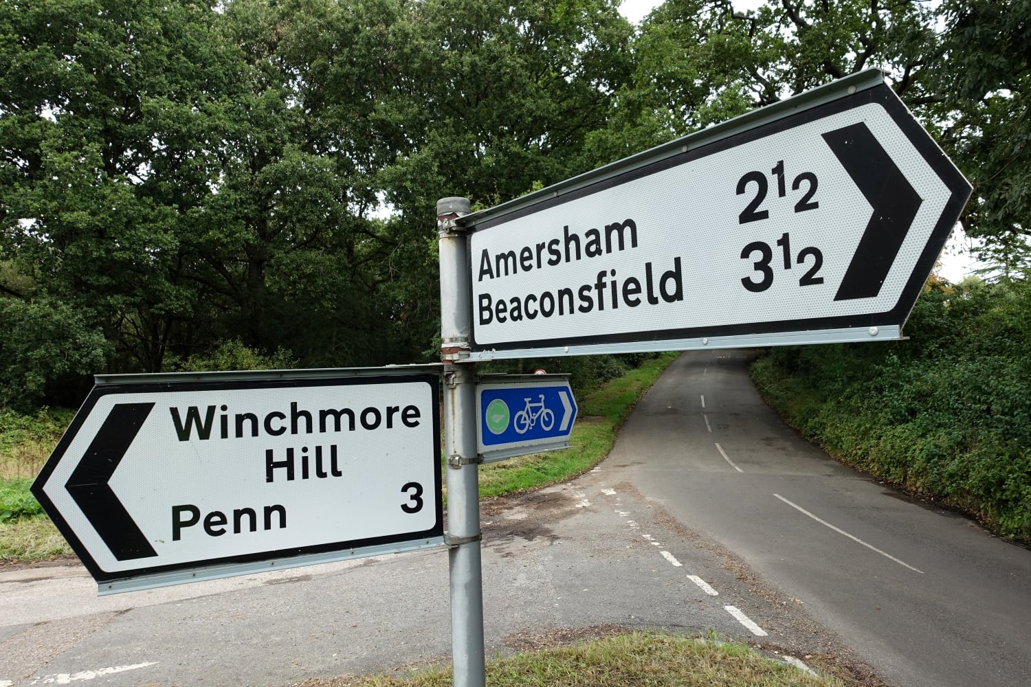 A road sign pointing to Amersham, Beaconsfield, Winchmore Hill, and Penn.