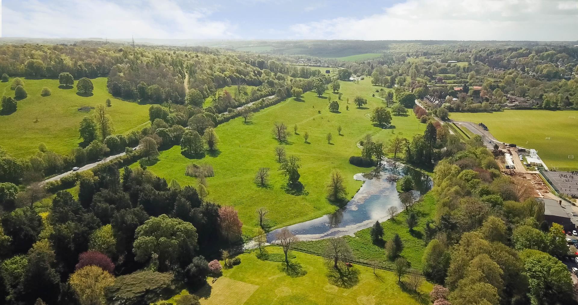 An aerial view of rolling green hills, a road and a lake in Great Missenden.