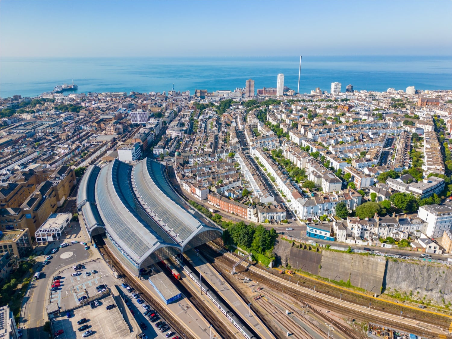 An aerial view of Brighton focused on the railway station, with blue sea in the background.