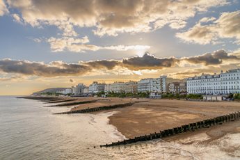 A beach in Eastbourne at sunset with buildings along the seafront.