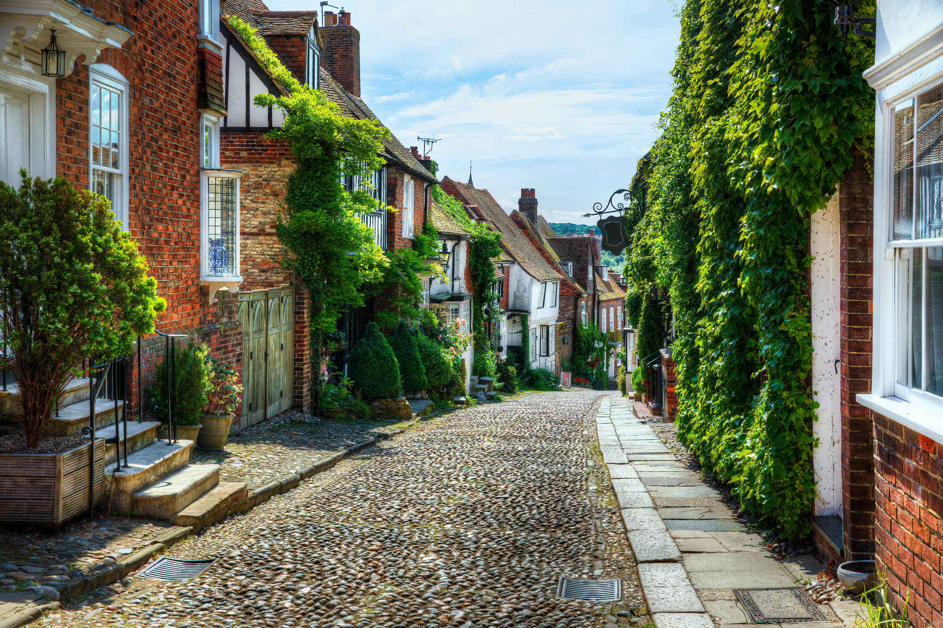 A cobbled street in Rye, East Sussex, with ivy growing over the buildings.