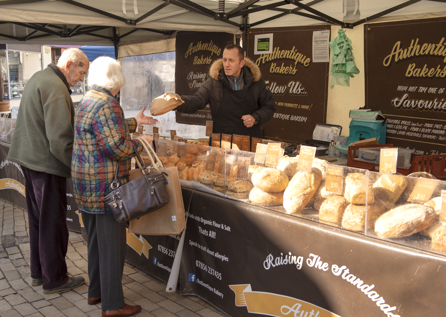 Two retirees buying bread at a local market in Romsey
